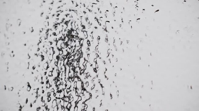 Abstract frozen rain droplets streaming down glass surface creating natural water texture pattern