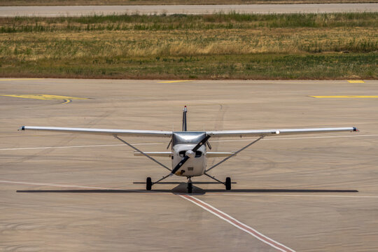 Small single engine propeller airplane taxiing on airfield runway during warm daylight