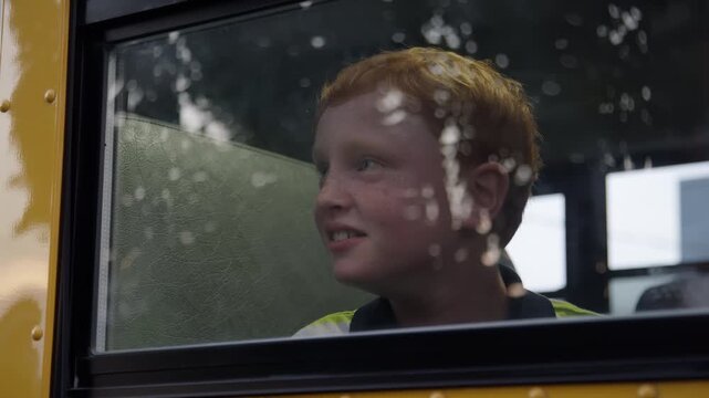redhead kid looking out school bus window