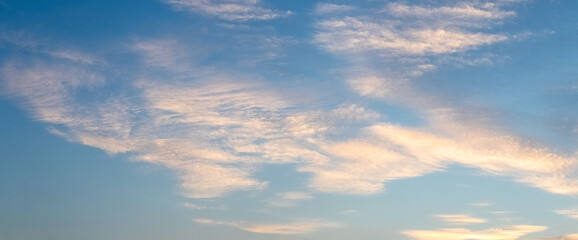 Obraz premium Panoramic blue sky with delicate cirrus clouds in warm evening light