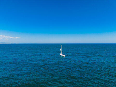 Sailboat moves across the blue ocean under a clear sky during midday