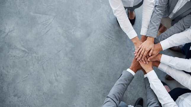 Business team stacking hands together in unity gesture from above