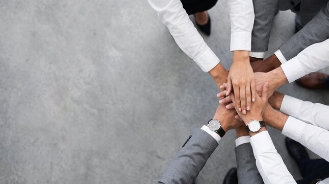 Business team stacking hands together in office unity gesture, top vie