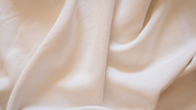 Soft, flowing beige fabric with gentle folds and subtle texture