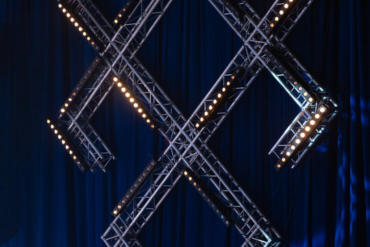 Crossed stage lighting trusses with blue curtain background