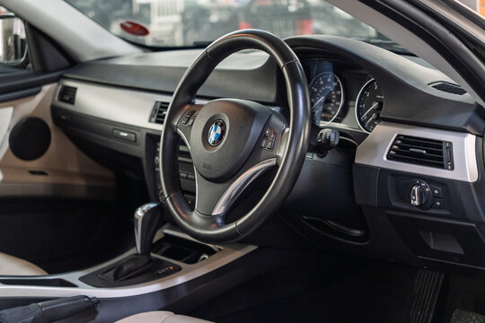 BMW 3 Series E92 German car interior dashboard cockpit close up, luxury luxury passenger automobile leather steering wheel with corporate brand logo badge, automatic transmission gear shifter. 
