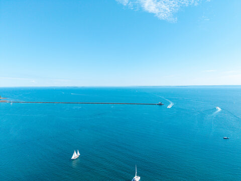 Aerial view of a two-masted schooner sailing past Rockland Breakwater Light and the long granite breakwater in Penobscot Bay near Rockland, Maine.