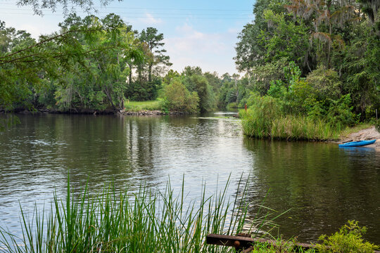 A blue kayak rests on the shore of the Waccamaw River near Riverfront Park and the Conway Riverwalk in Conway, South Carolina, in the Southeastern USA.