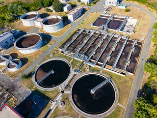 Overview of a wastewater treatment plant located in a suburban area showing large tanks and...