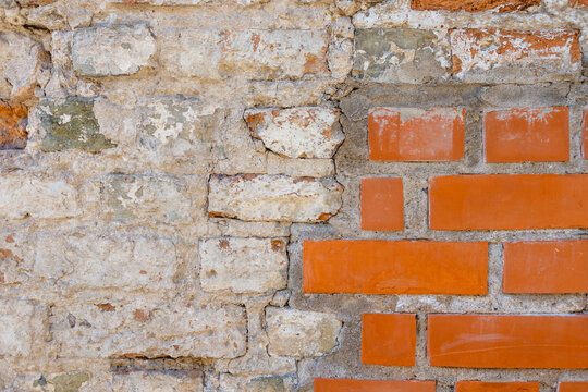 Close-up view of textured wall featuring a mix of rough stone and smooth red bricks. The surface shows signs of age and wear.