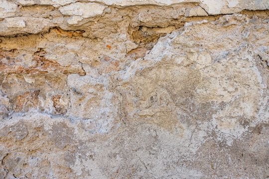 Textured wall with mix of beige and gray tones. The surface shows signs of wear and age, creating a rustic appearance.