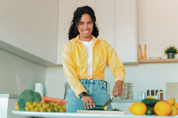 Smiling Black Woman Chopping Fresh Vegetables In Modern Kitchen, Engaged In Healthy Cooking,...