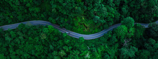 Obraz premium Aerial forest road with car creating abstract background for electric vehicle, ESG, sustainability and green investment business concepts.