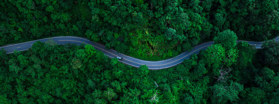 Aerial forest road with car creating abstract background for electric vehicle, ESG, sustainability and green investment business concepts.
