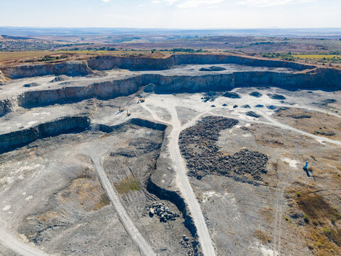 Granite quarry with large excavation areas and machinery in operation under clear sky in rural landscape