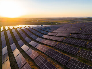 Solar panels capture sunlight on a farm in the late afternoon near a valley with a sunset in the...