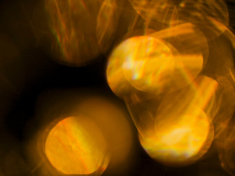 Abstract bokeh lights glow warmly against dark background. Soft, out-of-focus circles radiate golden hues. Ideal for holiday, dreamy, or cozy mood designs. Perfect for backgrounds, social media