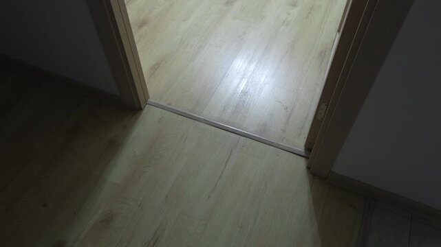 Laminate wood flooring and a doorway threshold inside a residential apartment, illustrating interior finishing, renovation and home improvement