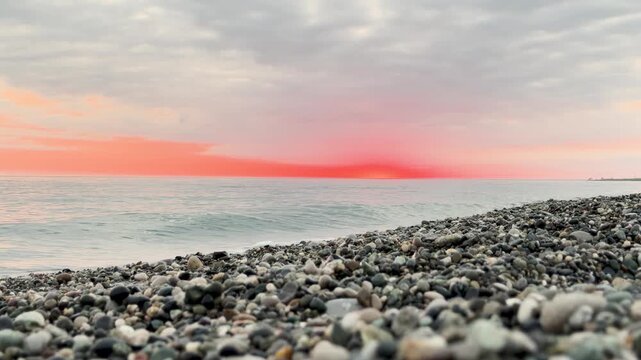Calm waves at sunset. Wave splashing over pebbles at sea with foam. Rolling ocean waves. Summer paradise beach background at sunset