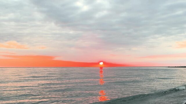 Calm waves at sunset. Wave splashing over pebbles at sea with foam. Rolling ocean waves. Summer paradise beach background at sunset
