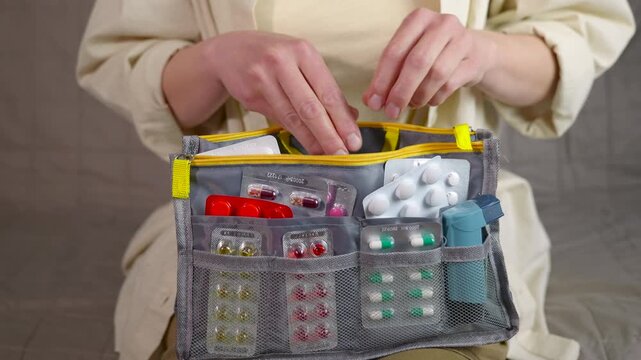Woman choosing contraception over pregnancy test. Young woman's hands choosing between a condom and a positive pregnancy test from her personal first aid kit, symbolizing a critical life choice