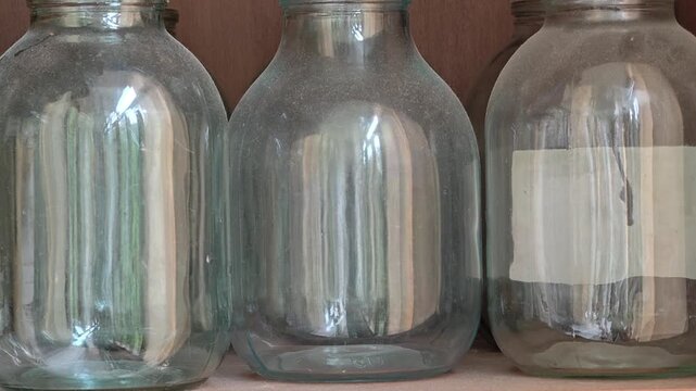 Row of empty glass bottles on a shelf, suitable for use in still life photography or as a decorative background