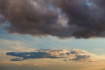 Obraz premium Beautiful sunset clouds in blue sky background, fluffy cumulus cloudscape illuminated by warm sun rays at golden hour evening, gentle peace and hope atmosphere conceptual scenic nature wallpaper. 