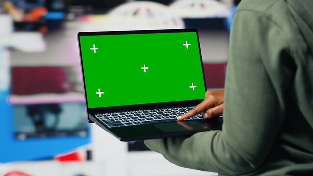 Woman uses a green screen mockup laptop to access video recommendations, watching digital clips on a chroma key notebook in a streaming context.