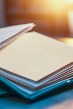 Papers stacked on a desk next to a cell phone, ideal for office or study scenes. vertical frame