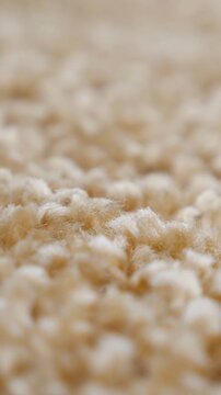 Detailed macro footage showing the soft, beige texture of a fluffy carpet, with the camera focus shifting smoothly across the warm, cozy fibers of the comfortable flooring material