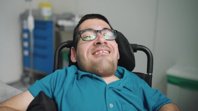 Portrait of a positive man with a physical disability smiling in his wheelchair. He is a patient in a hospital room during rehabilitation