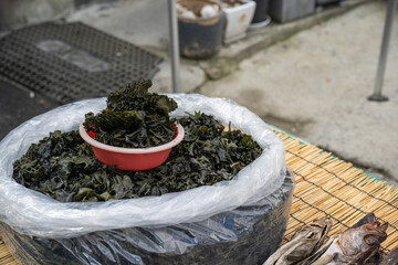 Dried Korean seaweed sporophyll mekabu displayed inside carton box for sale at outdoor traditional local street market in sunlight. © 완수 안
