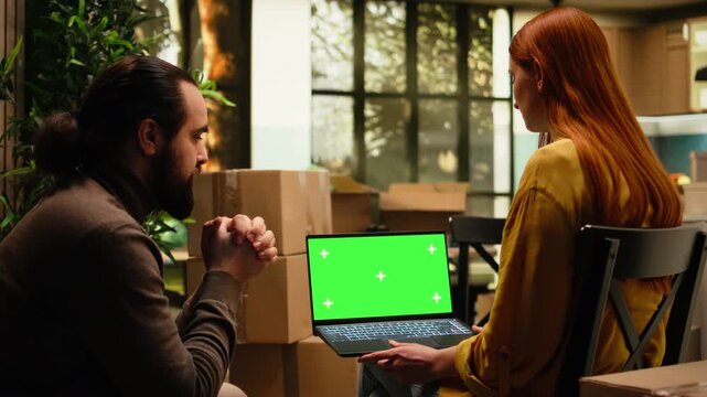 Laptop mockup sits with couple homeowners in their first home among boxes as they discuss room layout and redecoration ideas, plan interior design and begin a new chapter after moving in.
