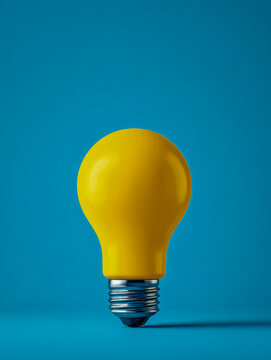 Bright yellow light bulb on vivid blue background symbolizing creativity inspiration and innovative thinking in minimalist style photography concept