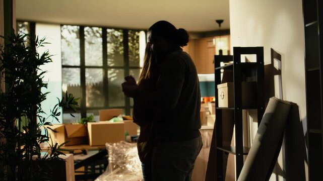 Romantic couple dancing and hugging indoors after finishing relocation, with happy homeowners celebrating the life event of buying property and starting a new chapter together in their first home.