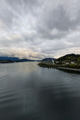 Fototapeta premium Overcast River Landscape With Small Boat and Industrial Shoreline Near Vancouver, BC, Canada