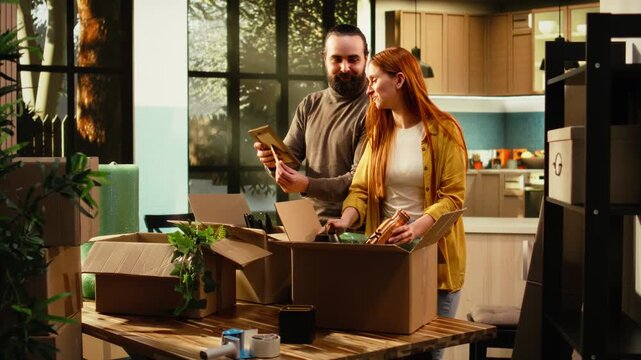 Man and woman unpack wrapped furniture and household items after relocation, arranging belongings in their new home as young homeowners enjoy an authentic moving-day lifestyle and fresh start.