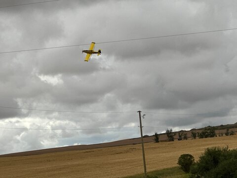 Small Agricultural Airplane Flying Low Above Open Farm Fields During Rural Alberta Farming Operations