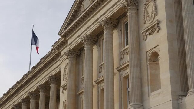 French flag flying over a government building with classical architecture and columns in Paris