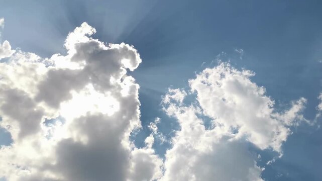 Sunbeams Shining Through White Clouds in Blue Sky