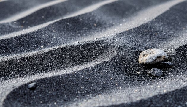 Close-up view of textured black and white sand dunes with small pebbles, showcasing natural patterns and contrasting grains.