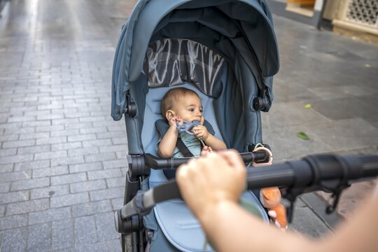 Mother pushing baby stroller on a cobblestone street