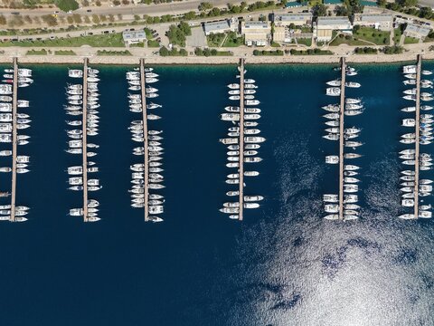 Top-down aerial view of a marina with white luxury yachts and boats docked at perfectly aligned piers in deep blue water.

Se&ccedil;enek 2 (&Ccedil;evre Odaklı): Bird's-eye view of a modern harbor showing parallel