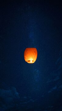 Solo glowing lantern ascending into night sky with stars