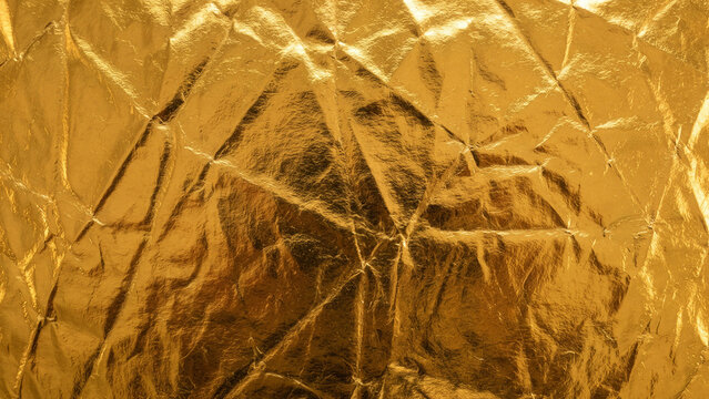 Crumpled shiny golden foil paper texture background
