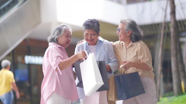 Group of Happy Asian active senior woman travel and shopping at department store in the city. Healthy elderly women friends enjoy and fun urban lifestyle holding shopping bag at shopping mall