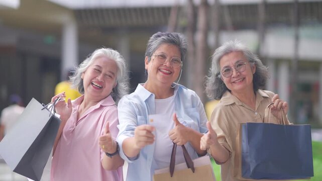 Group of Happy Asian active senior woman travel and shopping at department store in the city. Healthy elderly women friends enjoy and fun urban lifestyle holding shopping bag at shopping mall