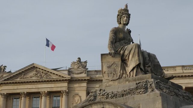 Rouen statue in Place de la Concorde with a French flag flying above a building