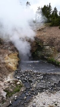 Dragon's Mouth Spring with boiling water and steam rising geothermal feature in Hayden Valley, Yellowstone National Park, summer vacation destination for outdoor nature recreation
