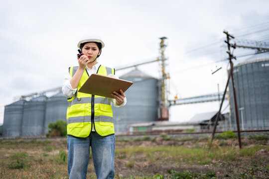 Female civil engineer in hard hat and safety vest inspecting industrial facility site